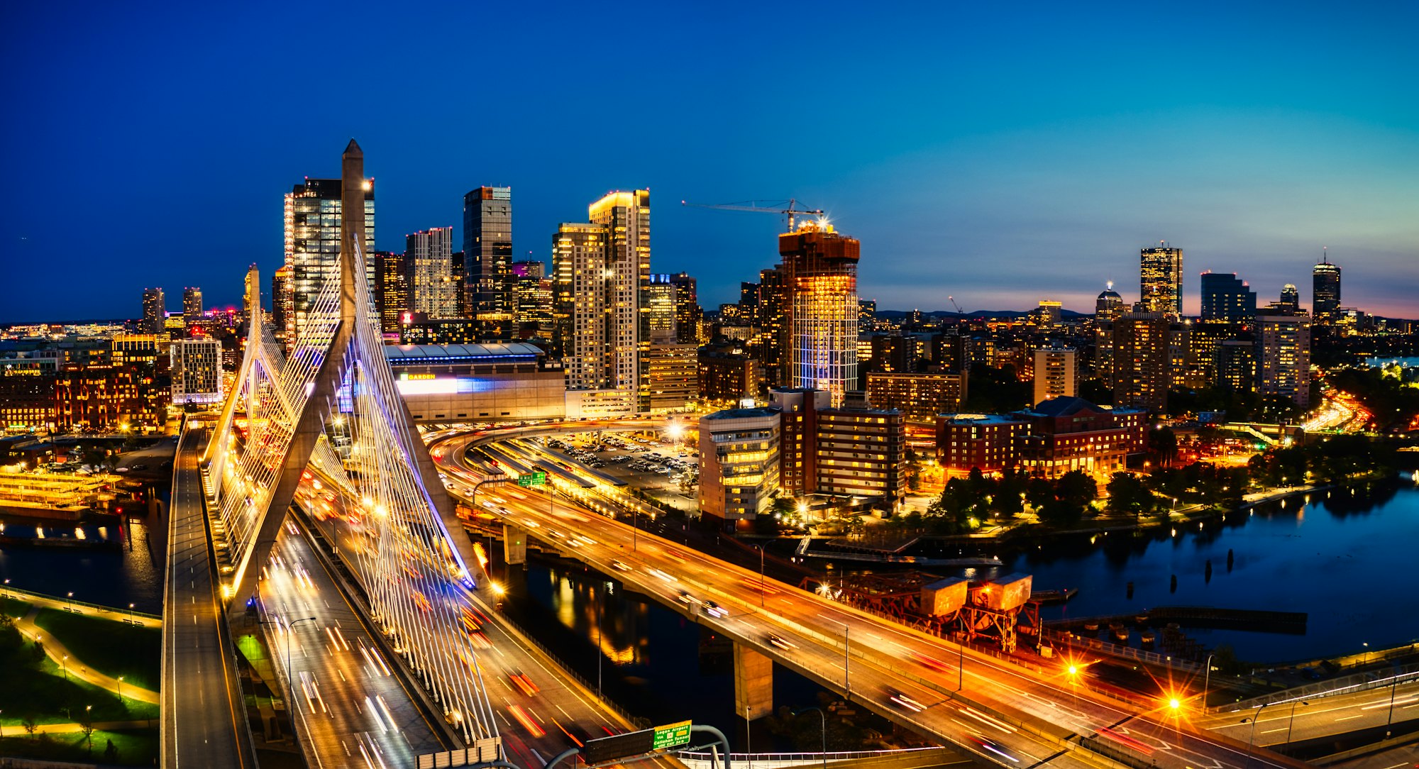Light trails across the Zakim Bridge in front of the Boston skyline at night