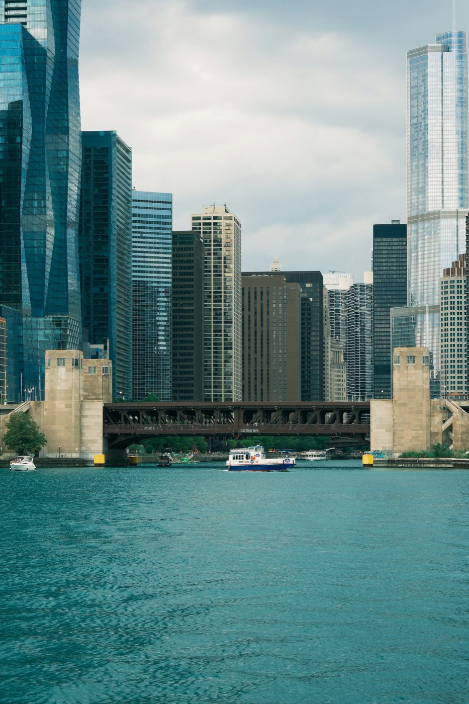 A boat on the Chicago River passing under a bridge between downtown towers