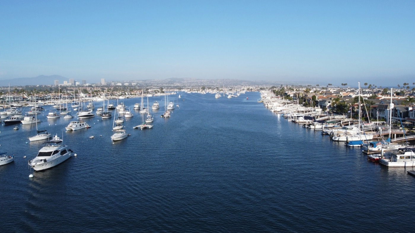 Aerial view of Newport Harbor with boats moored along the channel and homes on both sides