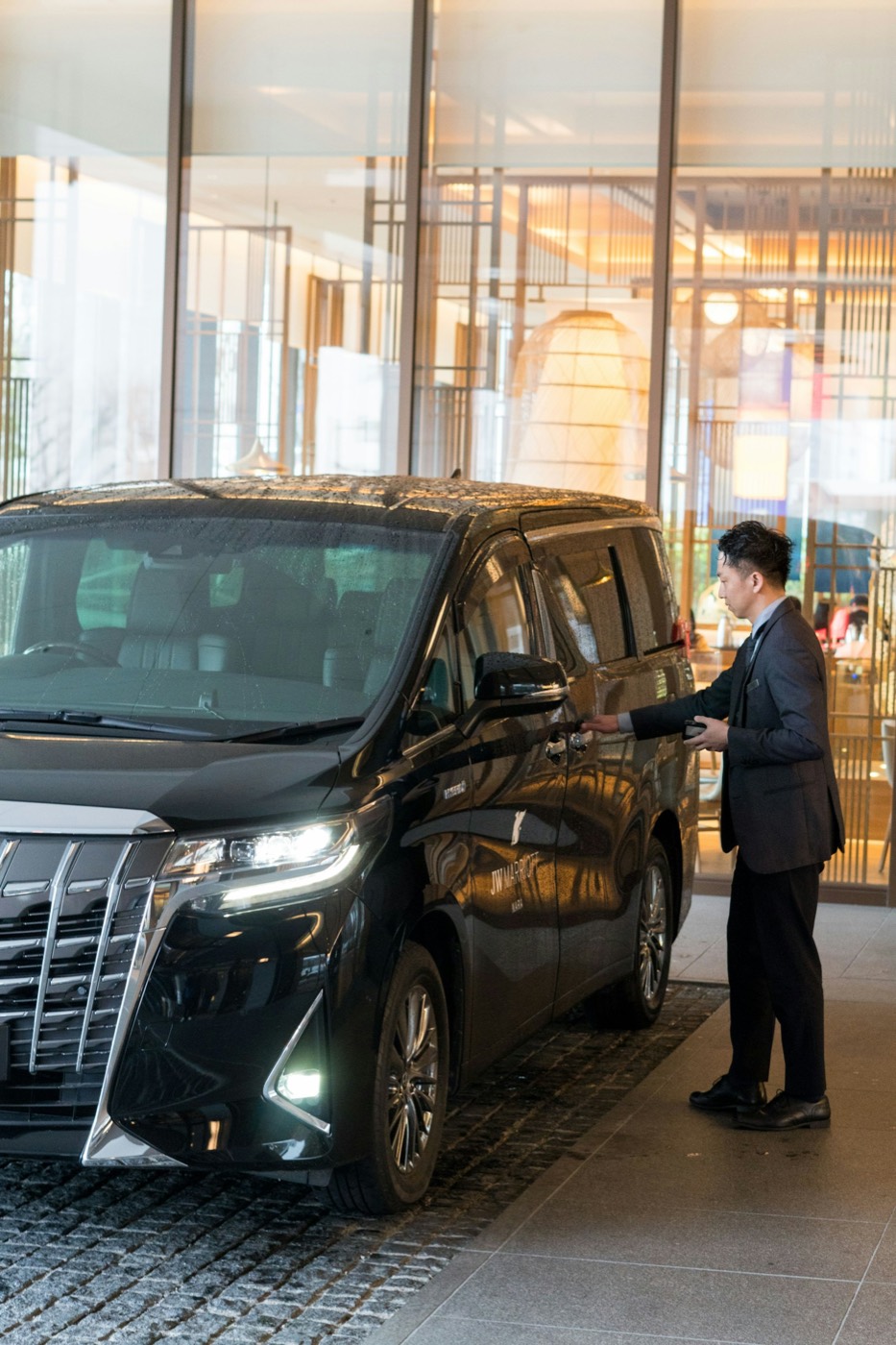 A chauffeur opening the car door for a client outside a hotel