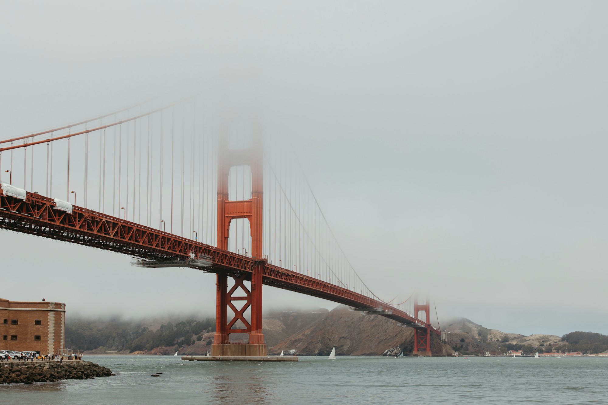The Golden Gate Bridge disappearing into the fog above San Francisco Bay