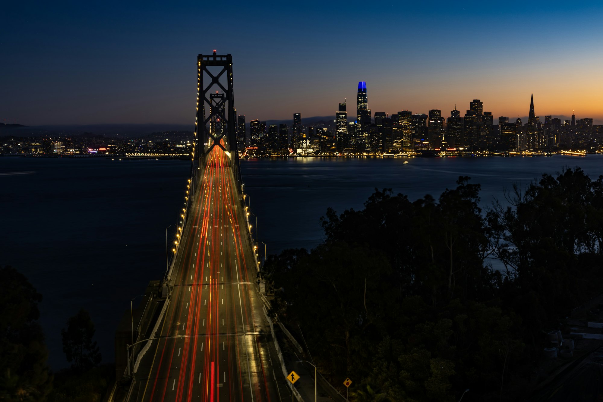 Light trails on the Bay Bridge leading to the San Francisco skyline at dusk